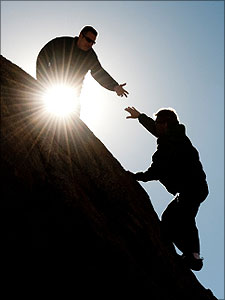 man helpt andere man om een berg te beklimmen